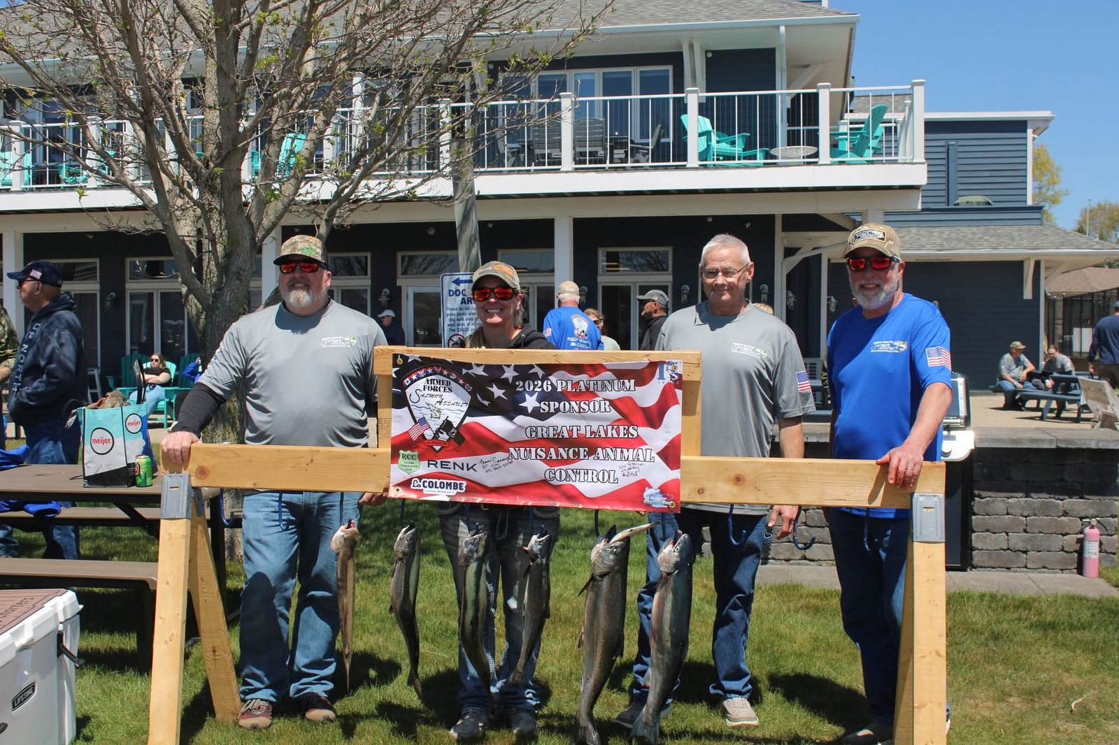 Veterans and sponsors with caught salmon holding a 2026 Platinum Sponsor banner