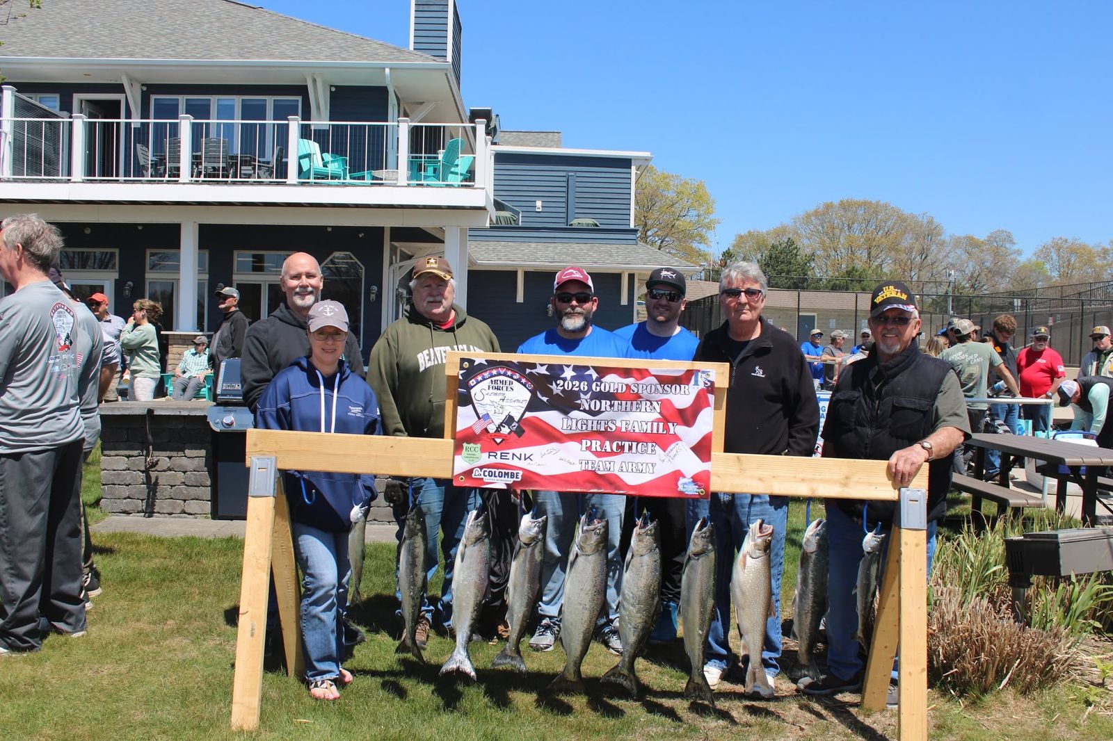 Participants displaying their catch of salmon in front of a 2026 Gold Sponsors banner