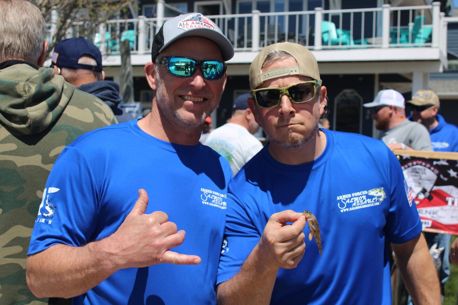 Two veterans in blue event T-shirts holding a salmon at the Armed Forces Salmon Assault
