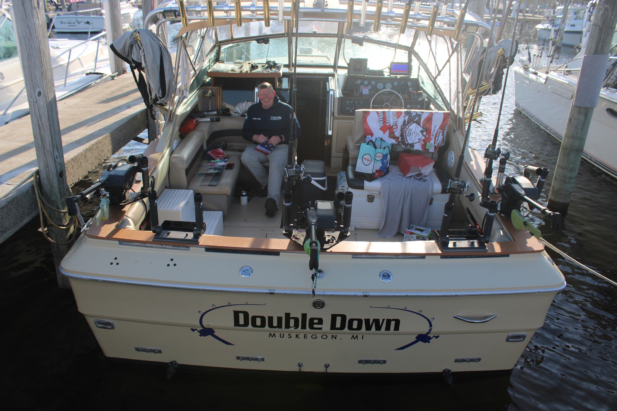 The 'Double Down' charter fishing boat docked in Muskegon, Michigan, with captain aboard and fishing equipment visible on deck.